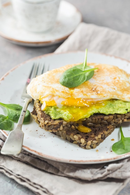 Sándwich con huevo de aguacate y espinacas sobre fondo de madera blanca desayuno dieta saludable