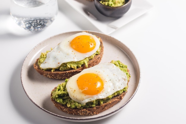 Sándwich de huevo de aguacate con un vaso de agua. Concepto de desayuno ligero y saludable. Tostadas integrales con