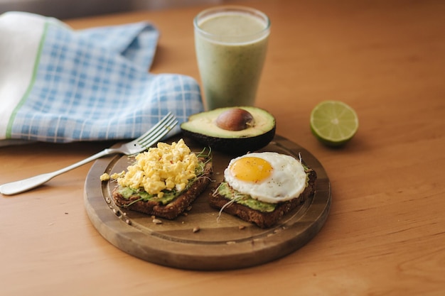 Sándwich de huevo cocido diferente sobre aguacate con pan integral sobre tabla de madera Batido con espinacas