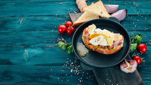 Sándwich con huevo escalfado, aguacate y queso parmesano Sobre un fondo de madera Espacio libre para texto Vista superior