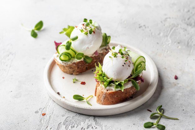 Foto sándwich de huevo escalfado con pepino y microgreens bruschetta de desayuno saludable sobre fondo claro espacio de texto de la dieta keto