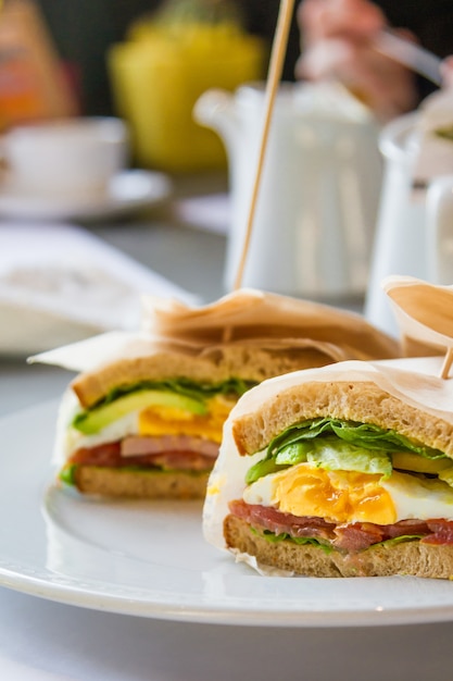 Sándwich con huevo, jamón, aguacate en restaurante.