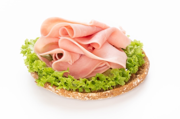 Sándwich de jamón de cerdo sobre superficie blanca.