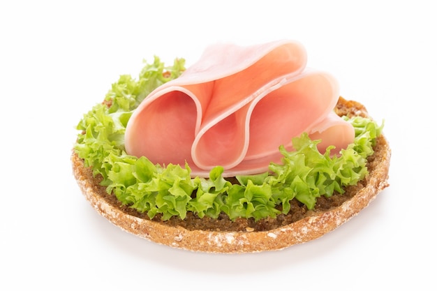 Sándwich de jamón de cerdo sobre superficie blanca.