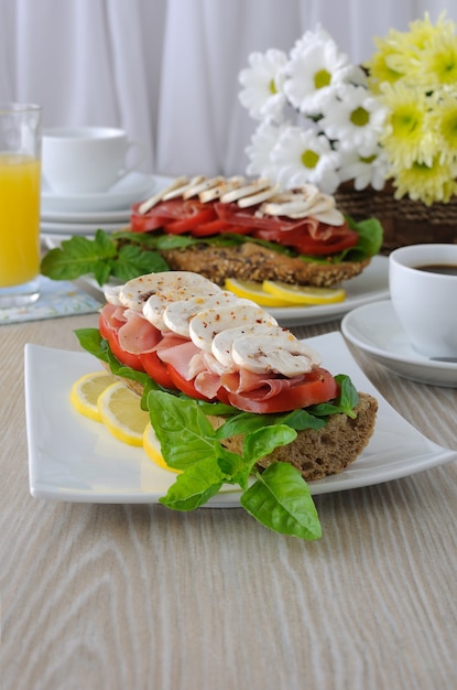 Sándwich de jamón y champiñones con una taza de café y jugo