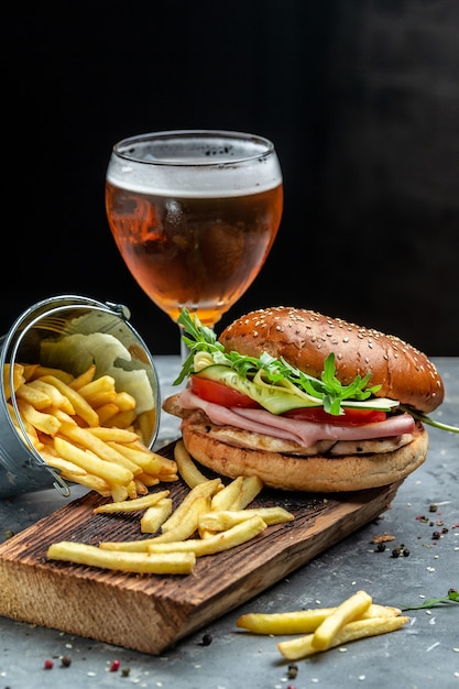 Sandwich de jamón. Hamburguesa con jamón, tomate y lechuga. Cerveza y papas fritas, hamburguesa con papas fritas y salsas. imagen vertical. lugar para el texto,