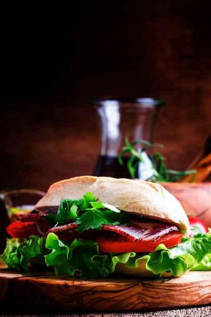 Sándwich con jamón, lechuga y tomate en pan de trigo enfoque selectivo de fondo de madera vintage