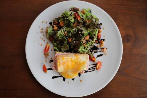 Sándwich de jamón y queso con ensalada sobre fondo de madera