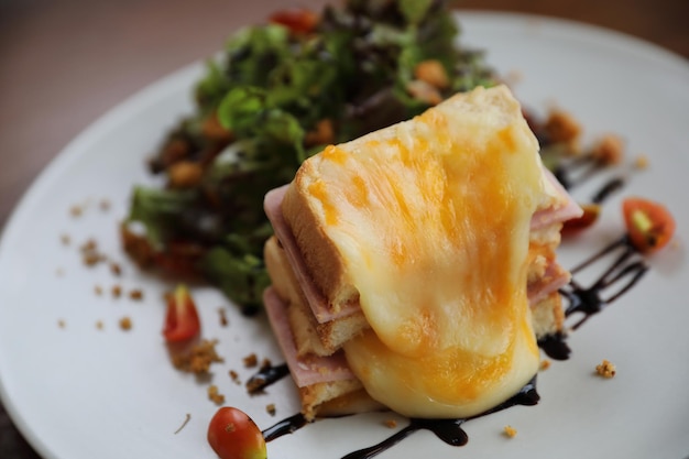 Sándwich de jamón y queso con ensalada sobre fondo de madera