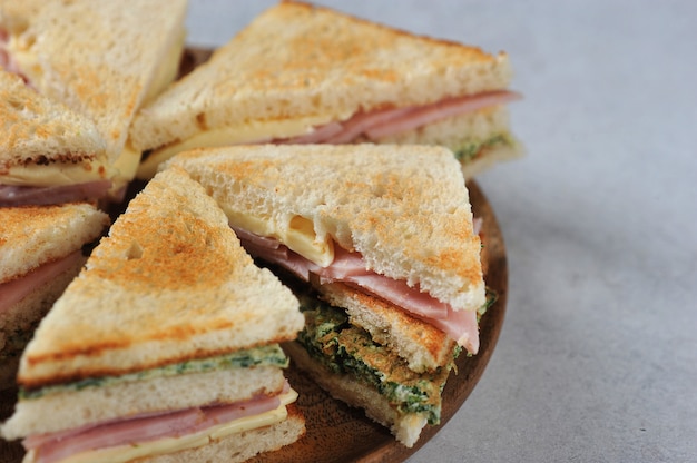 Sandwich de jamón y queso en un plato de madera