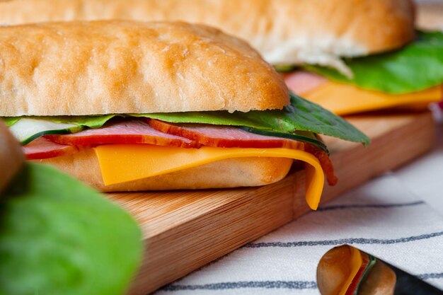 Foto sándwich con jamón y queso en tablero de madera