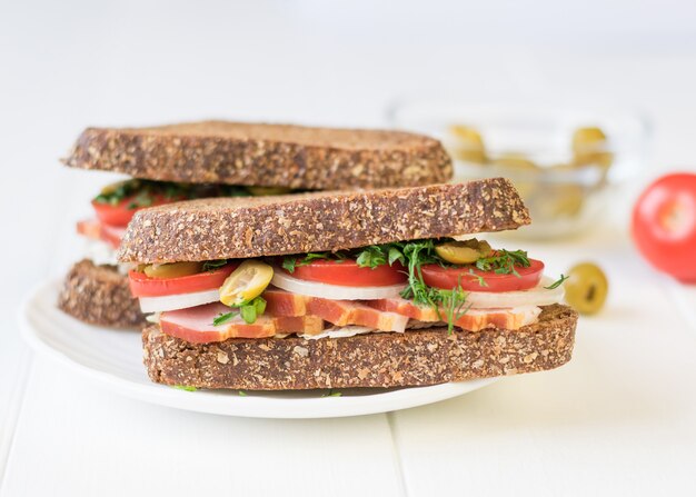 Sándwich de jamón recién hecho en una mesa de madera blanca.