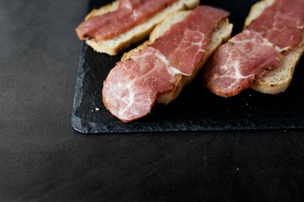 Sándwich con jamón seco sobre fondo negro pizarra de piedra Vista superior