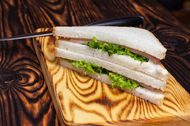 sándwich de jamón en una tabla de cortar sobre una mesa de madera oscura