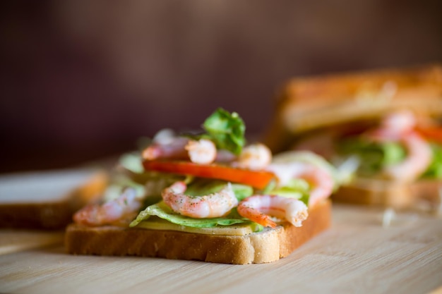 sándwich con lechuga y camarones sobre una tabla de madera