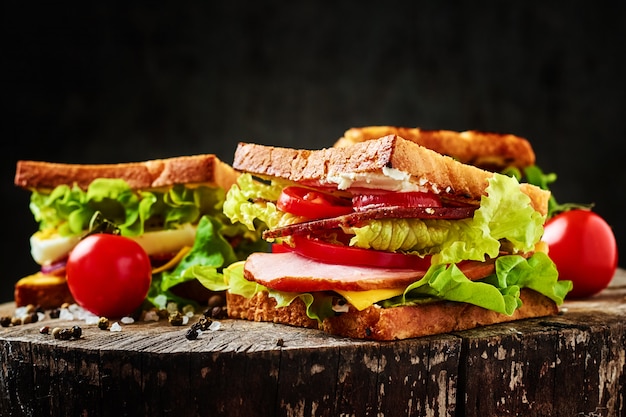 Sandwich con lechuga, jamón, tomate y cebolla en un oscuro primer plano