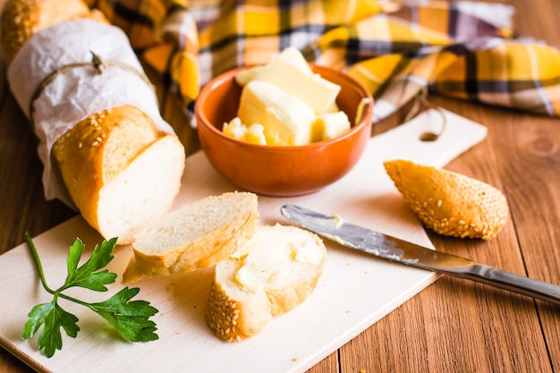 Sandwich con mantequilla y baguette en rodajas sobre una tabla para cortar