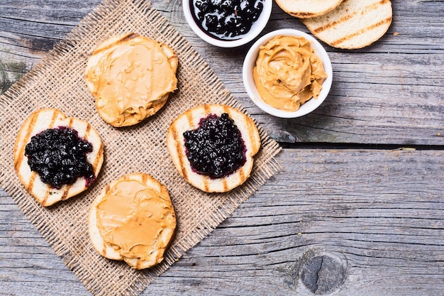 Sándwich de mantequilla de maní y mermelada sobre fondo rústico de madera