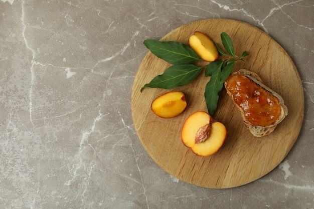 Sándwich con mermelada de melocotón e ingredientes en mesa con textura gris