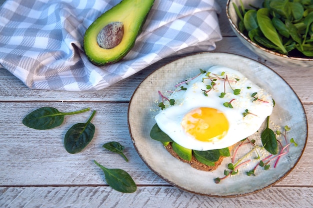 Sandwich mit Avocado, Ei, Spinat, Mikrogemüse und Sesam. Gesunde Ernährung, reich an Ballaststoffen, gesunden Fetten, Vitaminen, Spurenelementen