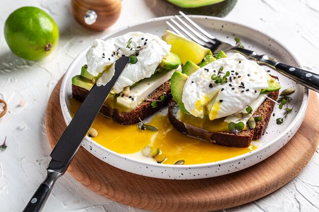 Sandwich mit Avocado und pochiertem Ei Vollkornbrot Toast geschnittene Avocado und Ei mit einer Tasse Kaffee für ein gesundes Frühstück oder einen Snack