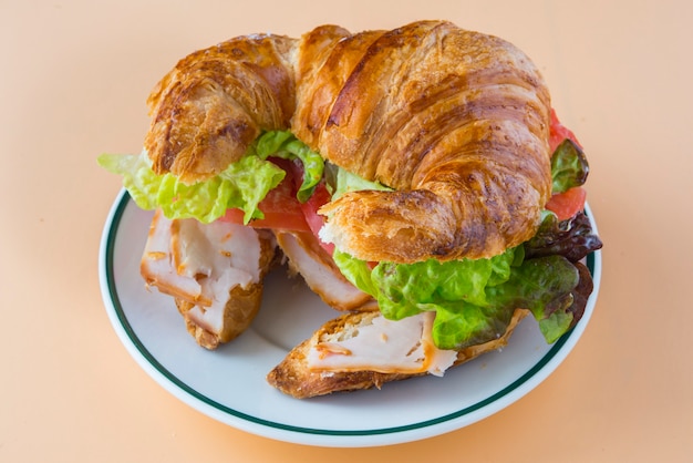 Sandwich mit Croissant aus Salat, Tomate und geräuchertem Truthahn
