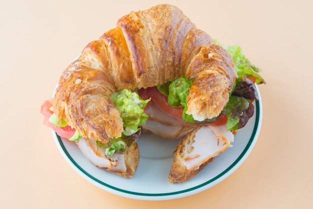 Sandwich mit Croissant aus Salat, Tomate und geräuchertem Truthahn