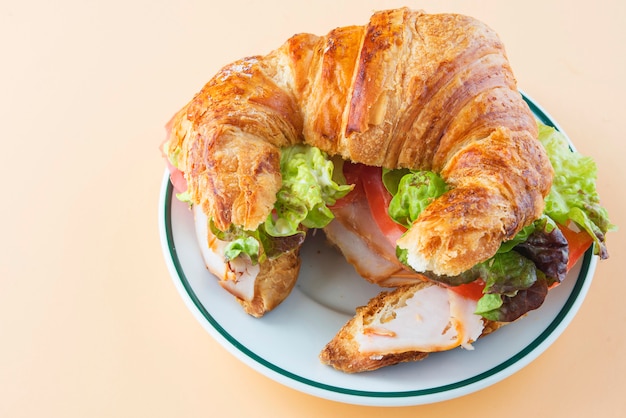 Sandwich mit Croissant aus Salat, Tomate und geräuchertem Truthahn