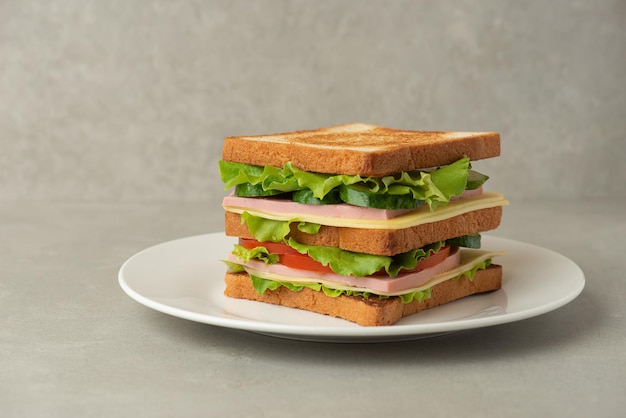 Sandwich mit Fleischkäse und Gemüse auf grauem Hintergrund
