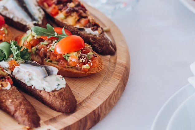 Sandwich mit Forelle, Kirschtomaten und Salat. Teller mit Snacks.