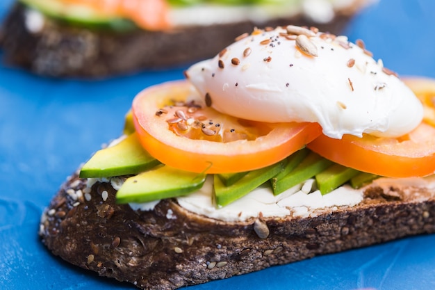 Sandwich mit geräuchertem Lachs, Ei und Avocado auf blauer Oberfläche. Konzept für eine gesunde Ernährung.