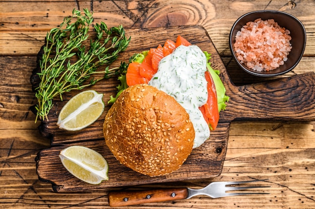 Sandwich mit gesalzenem Fischlachs, Avocado, Burgerbrötchen, Senfsauce und Eisbergsalat.