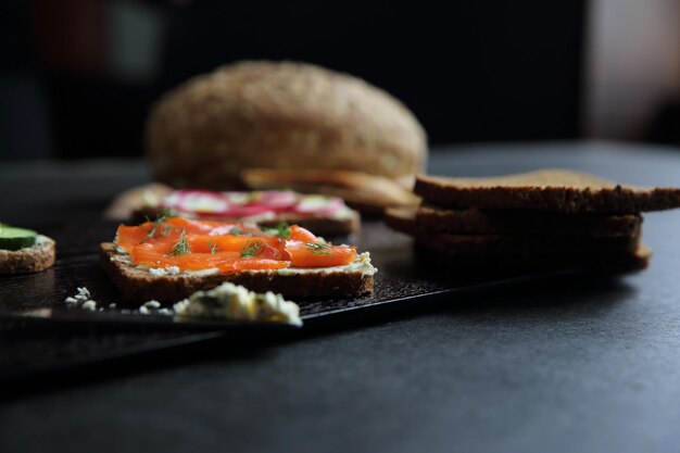 Sandwich mit Getreidebrot, geräucherter Lachs, Rote Beete und Gurke auf dunklem Marmorhintergrund