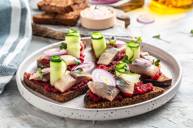 Sandwich mit Hering, rote Beete, grüne Gurke, Zwiebel und Mikrogrün. Dunkles Brot, Toast. Tradition der dänischen skandinavischen Küche