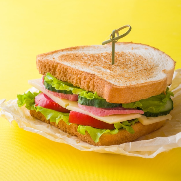 Sandwich mit Käse, Schinken und Frischgemüse auf gelbem hellem