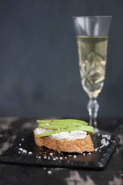 Foto sandwich mit käse und avocado, ein glas weißwein