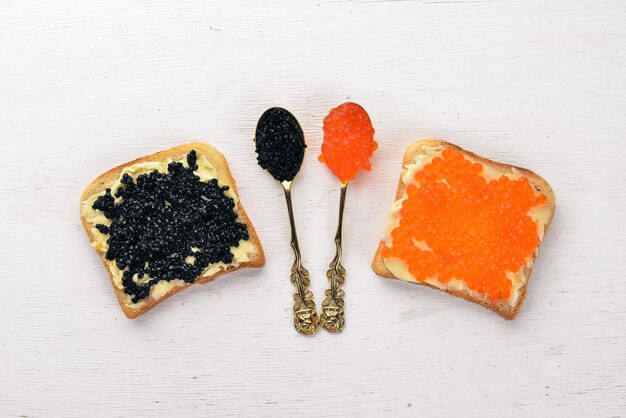 Sandwich mit Kaviar Kaviar auf einem Löffel Auf einem hölzernen Hintergrund Ansicht von oben Freier Platz für Text