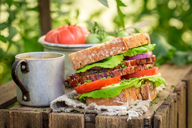 Sandwich mit Kopfsalattomate und -schinken im Gewächshaus