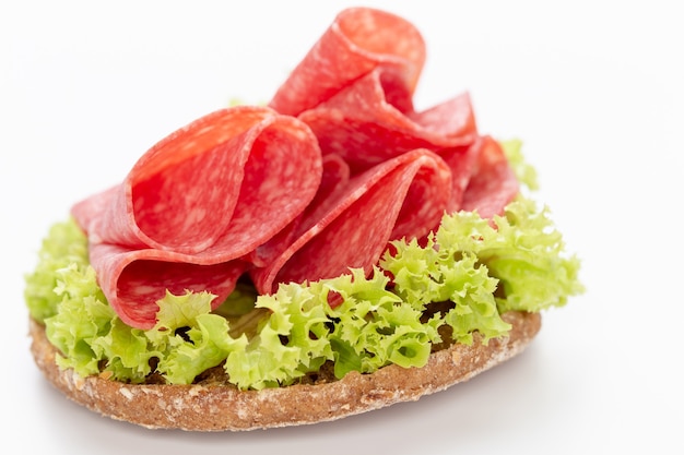 Sandwich mit Salami-Wurst auf weißem Hintergrund.