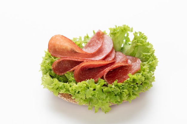 Sandwich mit Salami-Wurst auf weißem Hintergrund.