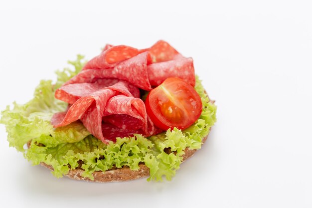 Sandwich mit Salami-Wurst auf weißem Hintergrund.