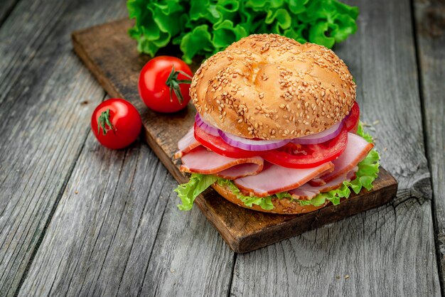 Sandwich mit Schinken und Gemüse auf einem alten Holztisch