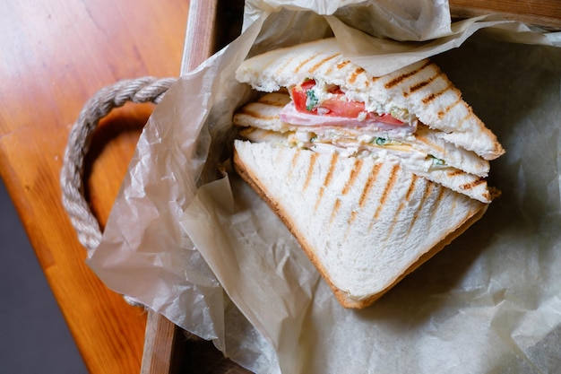 Sandwich mit Schinken und Gemüse auf Pergamentpapier Köstliches Mittagessen in der Nähe