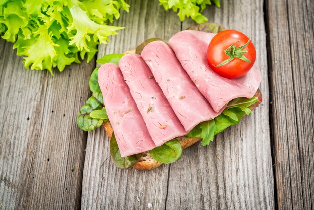 Sandwich mit Schinken und Gemüse. Bioprodukte auf einem Holztisch