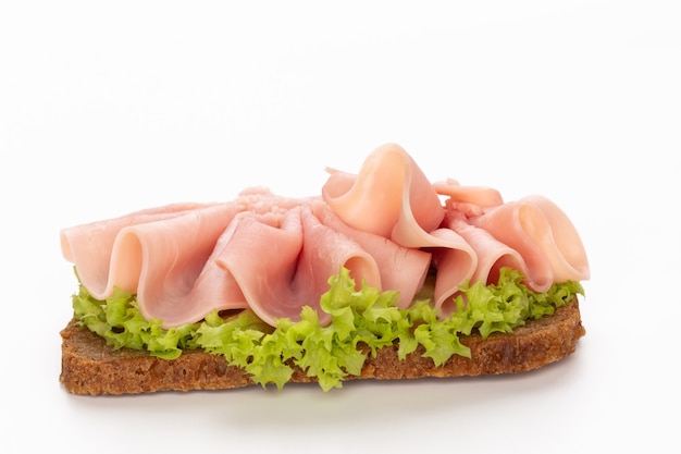 Sandwich mit Schweinefleischschinken auf weißer Oberfläche.