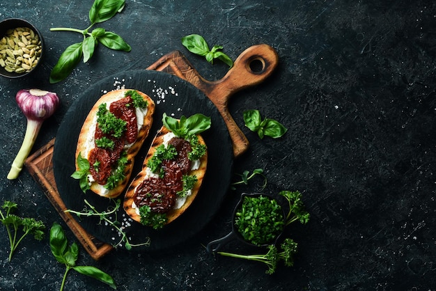 Sandwich mit sonnengetrockneten Tomaten, Käse und Basilikum Bruschetta Draufsicht auf einem Steinhintergrund