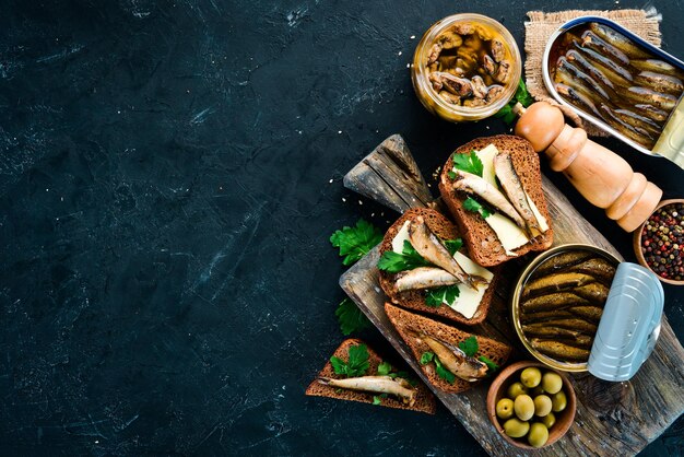 Sandwich mit Sprotte Sprotte in Öl auf einem schwarzen Hintergrund Draufsicht Freier Kopierraum