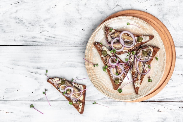 Sandwich mit Sprotten Zwiebeln Kapern und Microgreens Dänische Küche Banner Menü Rezept Ort für Text Draufsicht