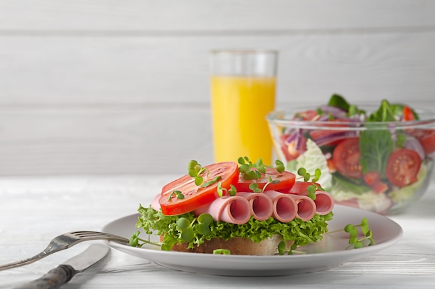 Sandwich mit Wurst und Tomaten mit Salat und Orangensaft Europäisches Frühstück