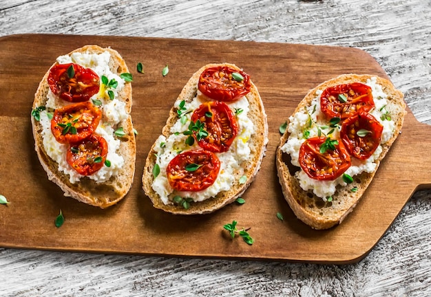 Foto sandwich mit ziegenkäse, sonnengetrockneten tomaten und thymian, serviert auf dem brett